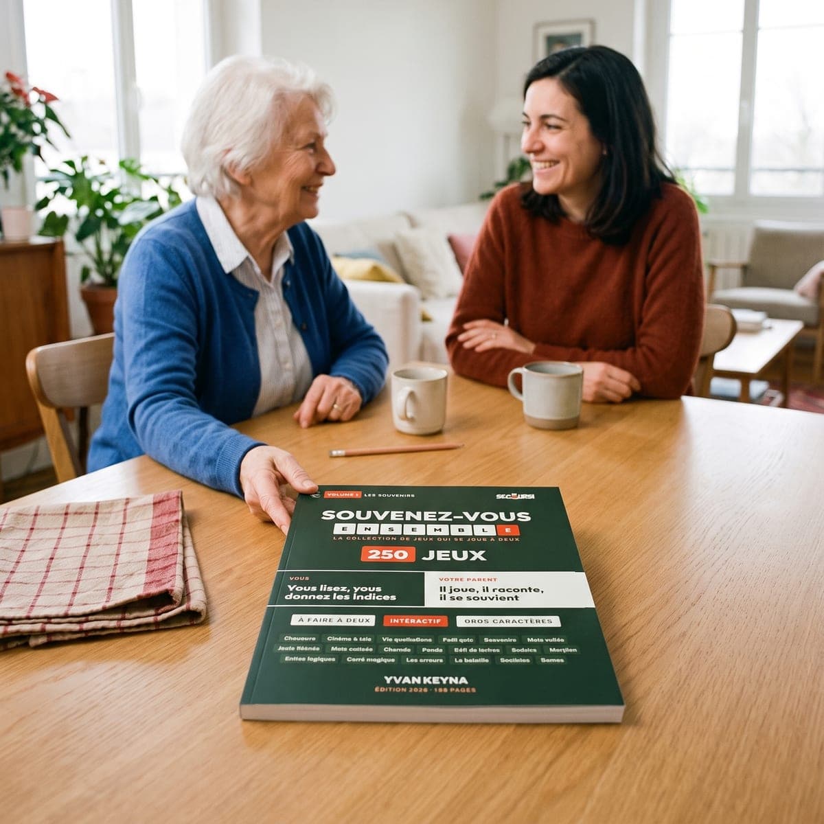 Una madre y su hija se ríen juntas a la mesa, con el libro «Recordemos Juntos» delante